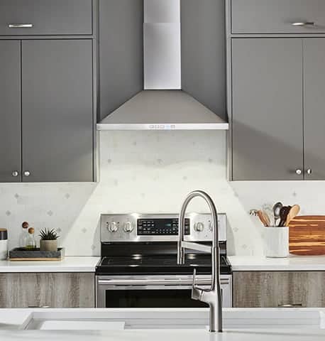 A kitchen view of the BROAN-NuTone BWP2306SS (30") Chimney Range Hood for our Top 5 Wall Mount Chimney Range Hoods of 2022 listicle. The range hood is installed in a kitchen.