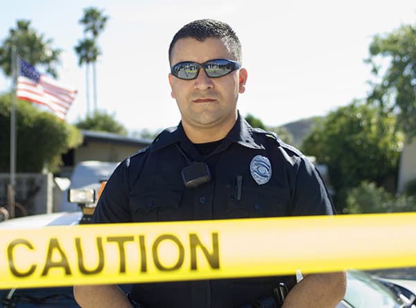 Police Officer Standing Behind Police Tape