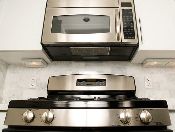 A stove with an over the range microwave above it. Next to the microwave are white cupboards.