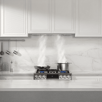 A frontal shot of the JOCO MYB01-30 range hood insert. It's stainless steel in color and has two baffle filters. It's integrated in a white kitchen cabinet. There's two pots underneath it with steaming coming off of them, which is sucked up by the range hood.