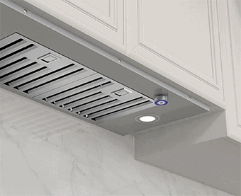 A bottom side shot of the JOCO MYB01-30 range hood insert. It's stainless steel in color and has two baffle filters. It's integrated in a white kitchen cabinet.