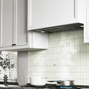 A kitchen shot of the VIKIO HOME VK-RB11-30GB range hood insert. It is integrated in a kitchen with white cabinets. There are two pots under it with steam coming off of them.