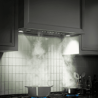 A kitchen shot of the VIKIO HOME VK-RB11-30GB range hood insert. It is integrated in a kitchen with white cabinets, but the shot is dark. It's taken in a dark room and the only source of light are the LED lights on the range hood.